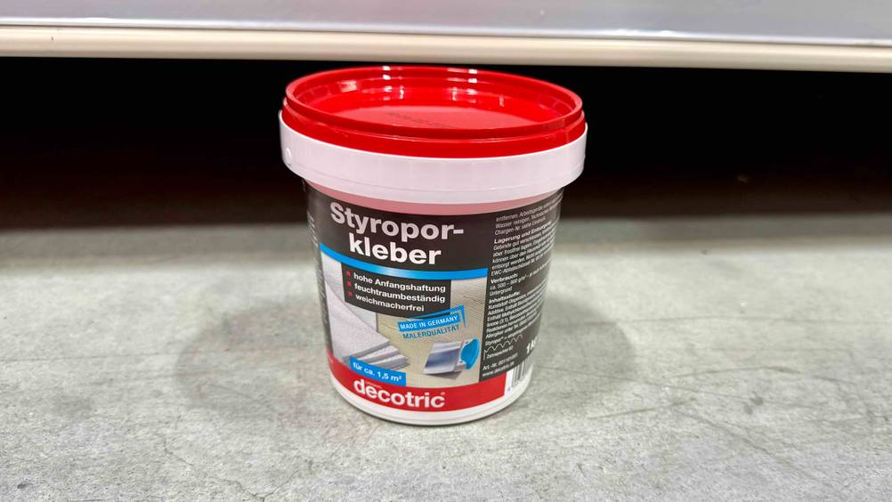 Vor einem Regal auf dem Boden steht der getestete Styroporkleber.