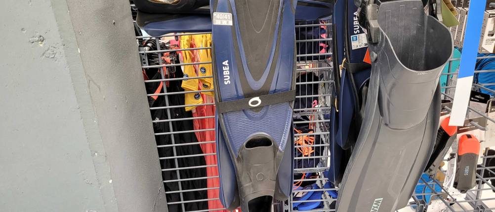 Mehrere Schwimmflossen hängen zum Testen nebeneinander an einem Lochregal.