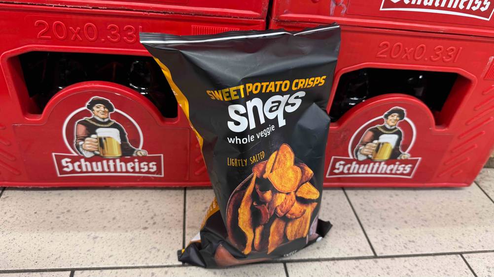 Süßkartoffel-Chips im Test: Eine Packung vor Getränkekästen auf dem Boden.