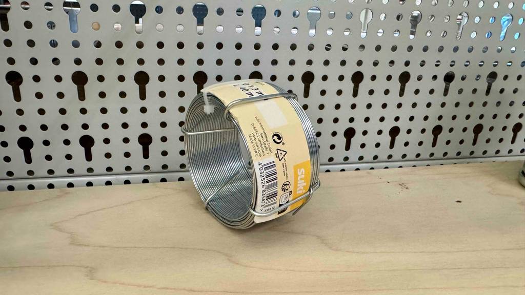 Eine Rolle Bindedraht liegt zum testen in einem Gitterregal.