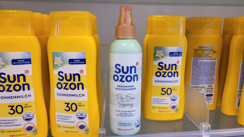 Eine hellgrüne Sprühdose mit Sun Ozon Bräunungsbeschleuniger im Test steht zwischen gelben Sun Ozon Sonnenmilch auf einem Verkaufsregal.