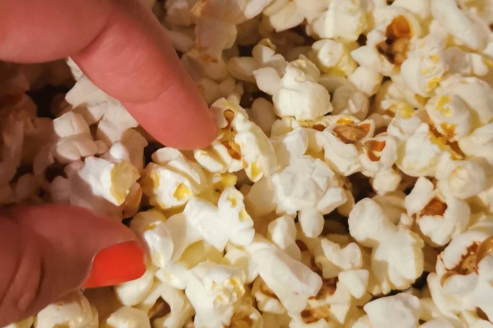 Eine Hand greift in den Sun-Snack-Popcornmais