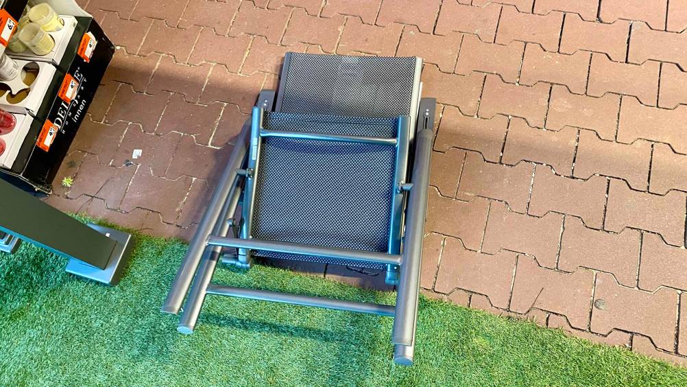 Alu-Klappsessel getestet: Ein zusammengeklapper Stuhl auf einer Steinfläche von unten.