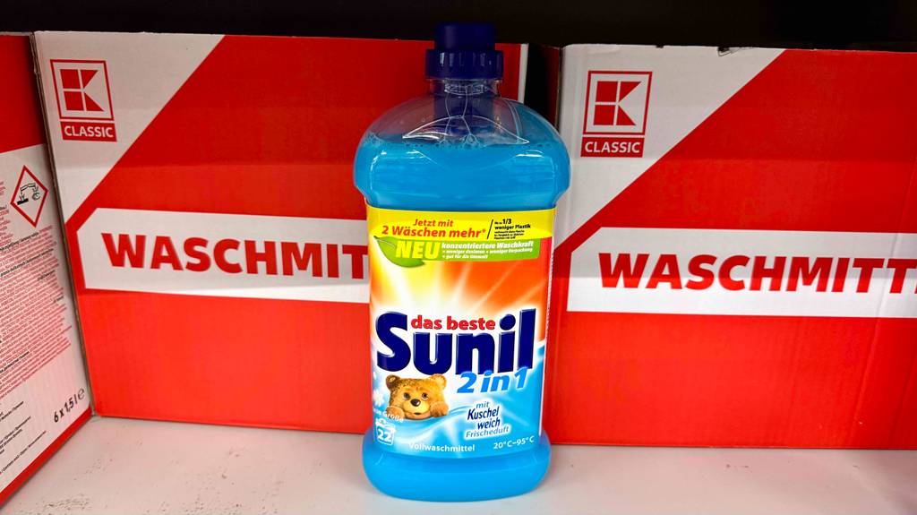 Flüssiges Vollwaschmittel im Test steht in der Flasche vor einem roten Waschmittel-Karton.
