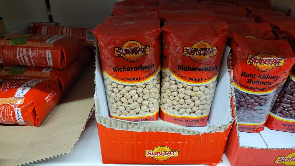 500-g-Packungen mit getrockneten Kirchererbsen im Test stehen in einem Karton auf einem Verkaufsregal mit Hülsenfrüchten.