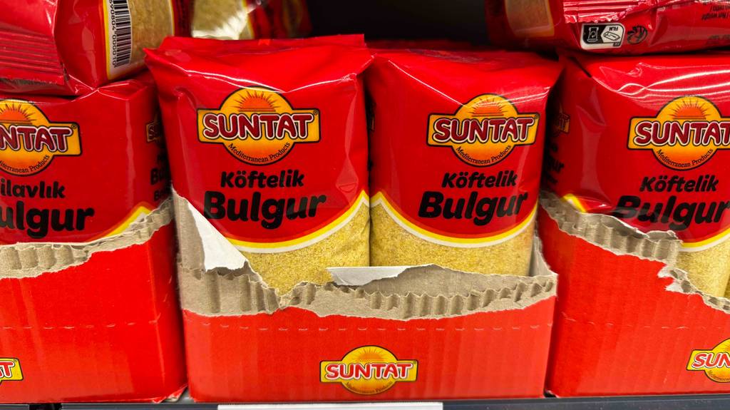 Im Test: Bulgur in mehreren 500-g-Packungen mit Sichtfenstern steht in einem Verkaufsregal.