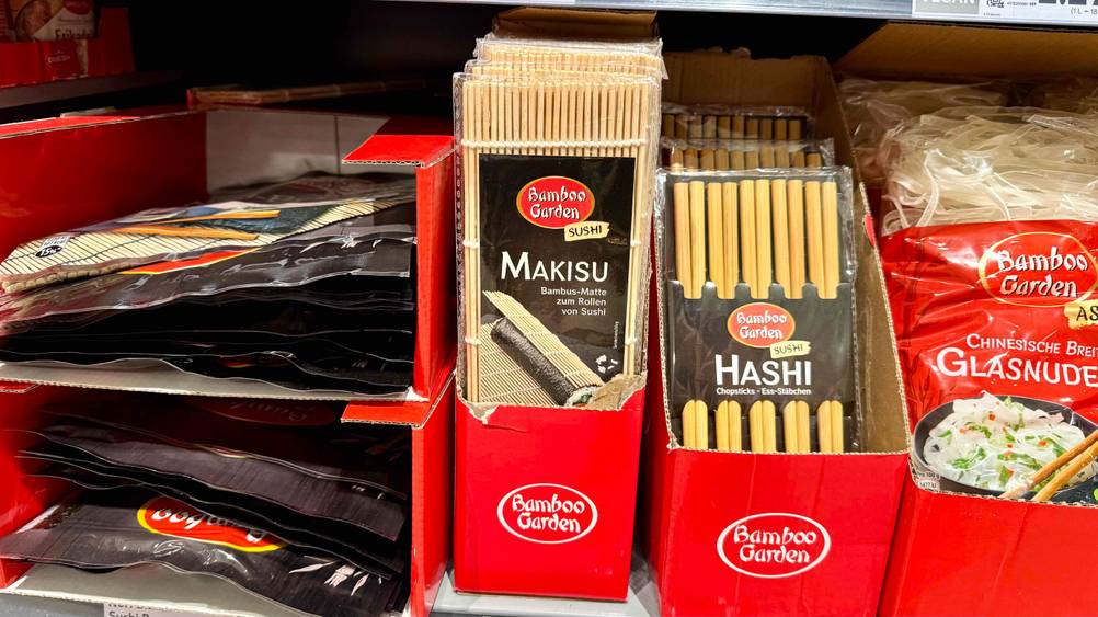 Mehrere der getesteten Sushimatten in einem Verkaufsregal neben anderen Produkten.