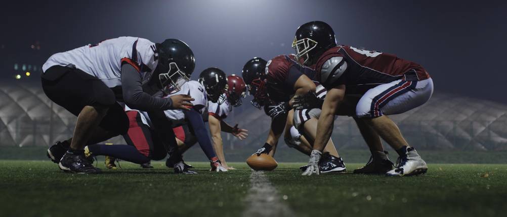 Suspensorium-Herren-Test: Football-Spieler stehen sich auf dem Football-Feld gegenüber.