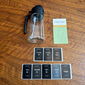 Der Lieferumfang vom Sweet-View-2-in-1-Ölsprüher liegt auf einem Tisch