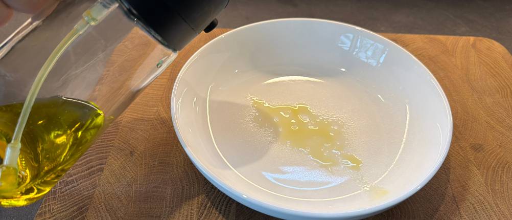 Mit dem Sweet-View-2-in-1-Ölsprüher wird Öl auf einen Suppenteller gesprüht