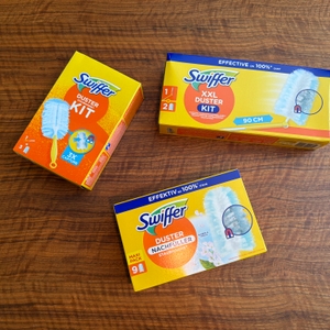 Drei Kartons vom Swiffer-Staubwedel liegen auf einem Tisch.