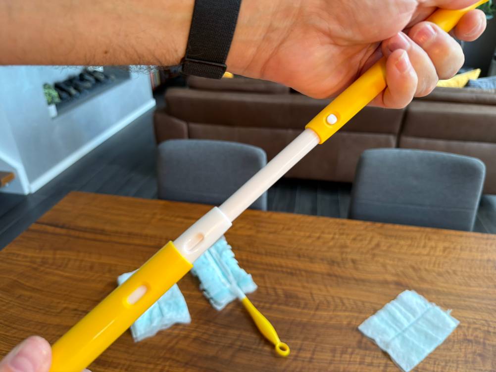 Eine Hand verlängert den Griff vom Swiffer-Staubwedel.