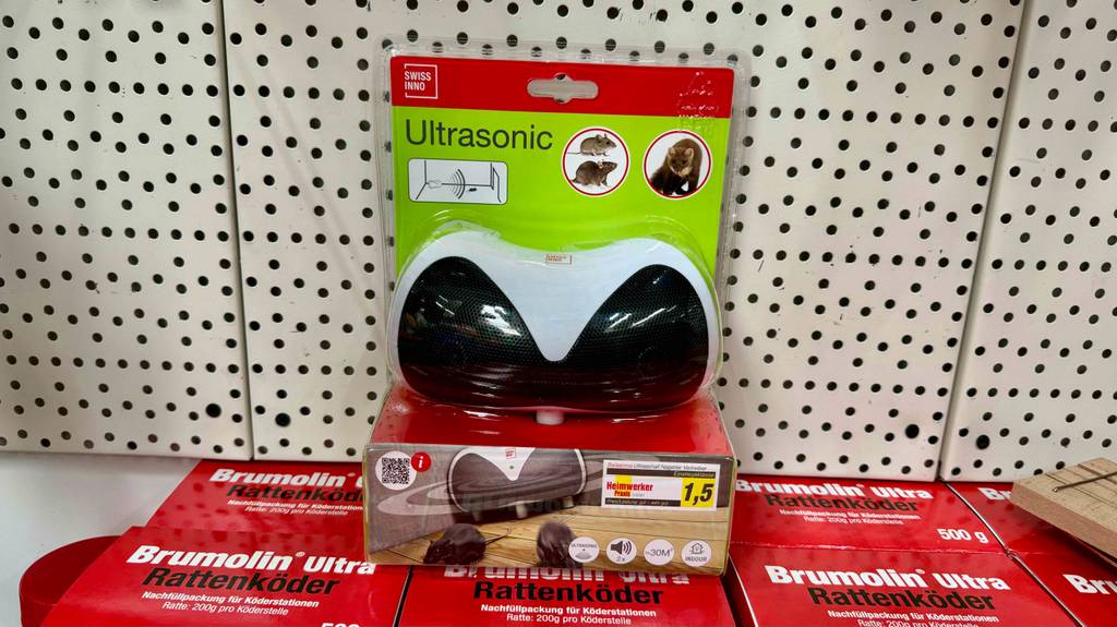 Auf mehreren roten Verpackungen mit Rattenködern steht eine Verpackung inklusive eines Ultrasonic Wühlmausvertreibers im Test.