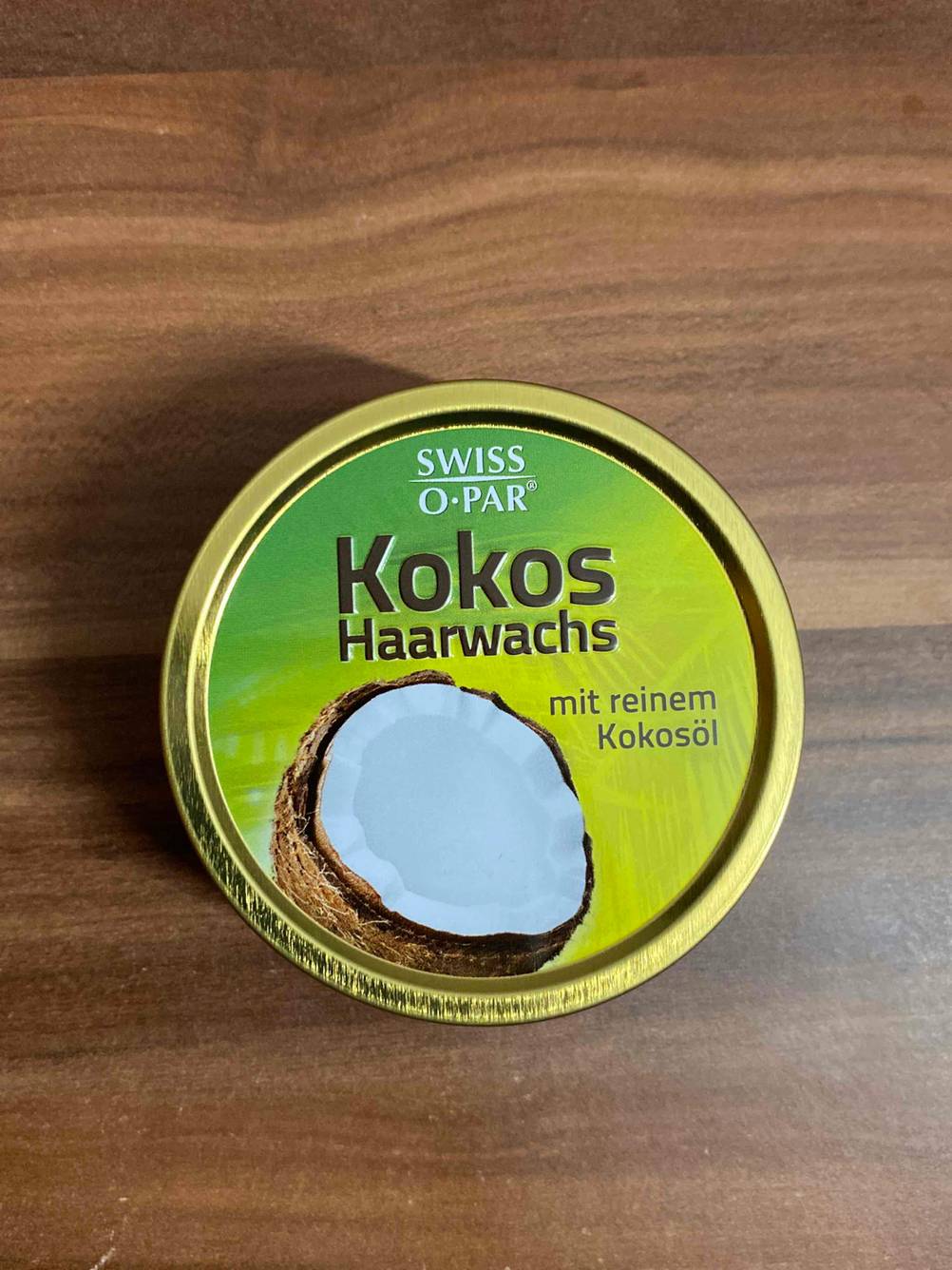 Ein Tiegel getestetes Haarwachs steht auf einer dunklen Holzfläche.