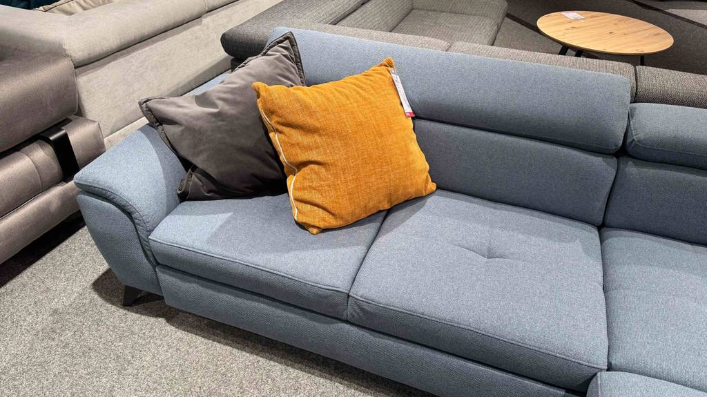 Ein getestetes Ecksofa mit grauem Stoffbezug steht inmitten einer Sofalandschaft im Geschäft.