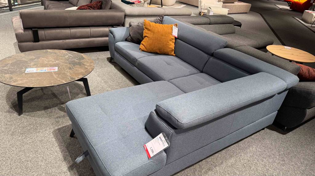 Im Test: Ein Ecksofa mit grauem Stoffbezug steht im Ausstellungsbereich eines Möbelhauses.