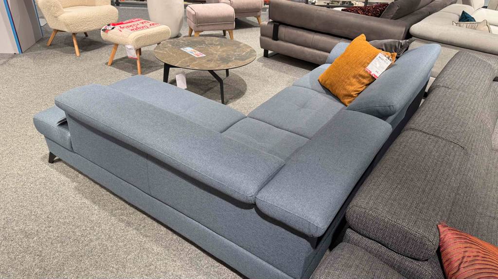 Ansicht von hinten über Eck auf ein getestetes Ecksofa mit grauem Stoffbezug.