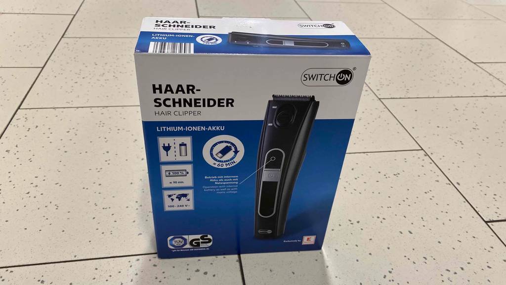 Akku-Haarschneider-Test: Haarschneider von SwitchOn steht in geschlossener Verpackung auf einem Fliesenboden.