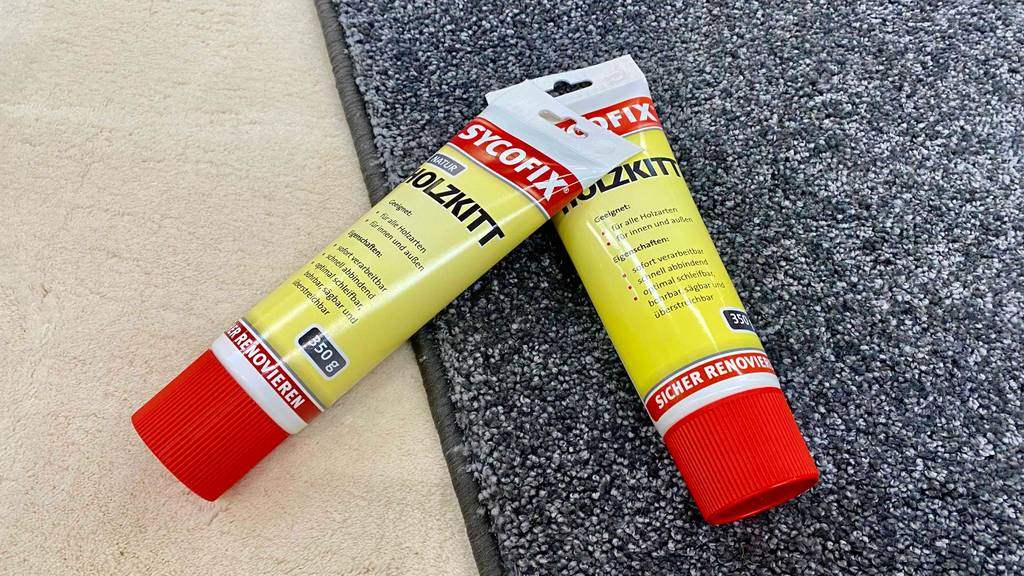 Im Test: Zwei Tuben Holzkitt liegen quer übereinander auf einem Fußabstreifer.
