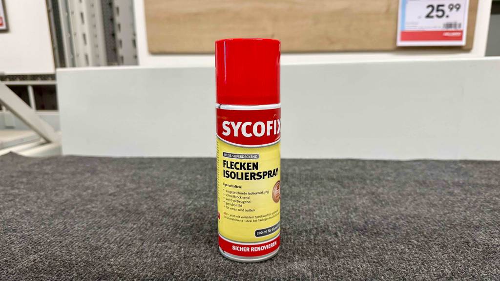 Das getestete Isolierspray in der 200-ml-Spraydose steht auf einem grauen Teppichboden.