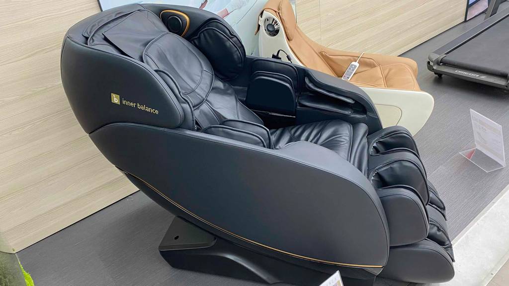 Seitliche Ansicht von einem schwarzen Massagesessel im Test inklusive Ganzkörpermassage-Funktionen in einem Verkaufsbereich.