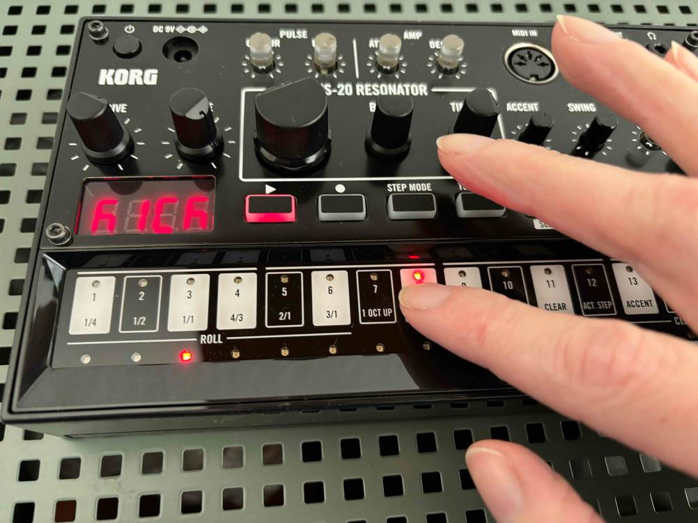 Eine Hand drückt einen Knopf an dem getesteten Synthesizer.