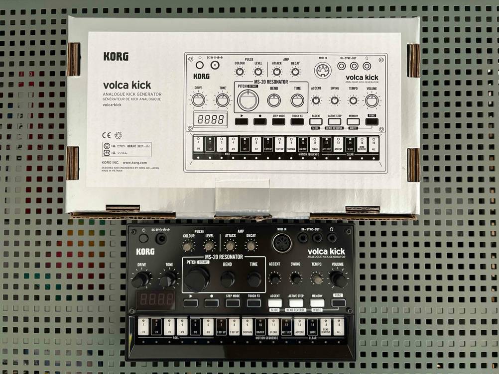 Synthesizer getestet: Die Originalverpackung und das Gerät übereinander liegend auf einem Lochblech.
