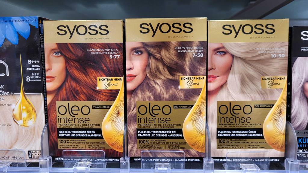 Mehrere Packungen mit Haarfarbe von Syoss im Test stehen nebeneinander im Drogeriemarktregal.