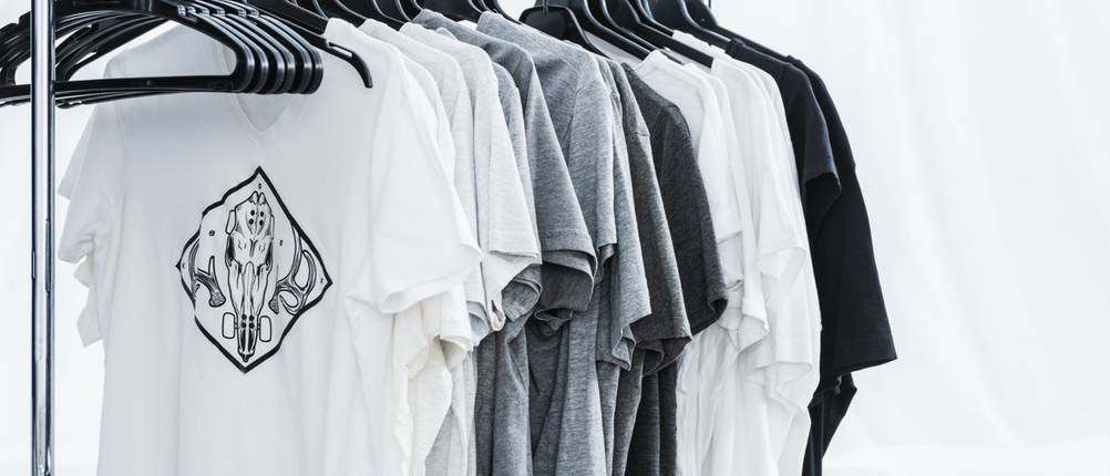 Bedruckte T-Shirts hängen auf Kleiderbügeln in einem Designstudio