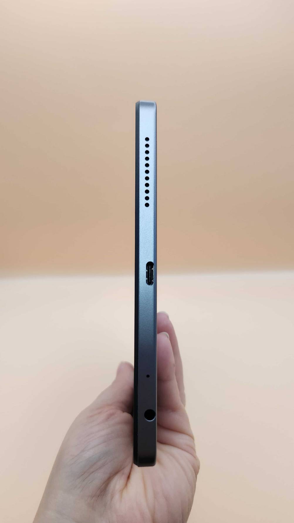 Die Unterseite des getesteten Tablet LTE mit Anschluss von einer Hand gehalten.