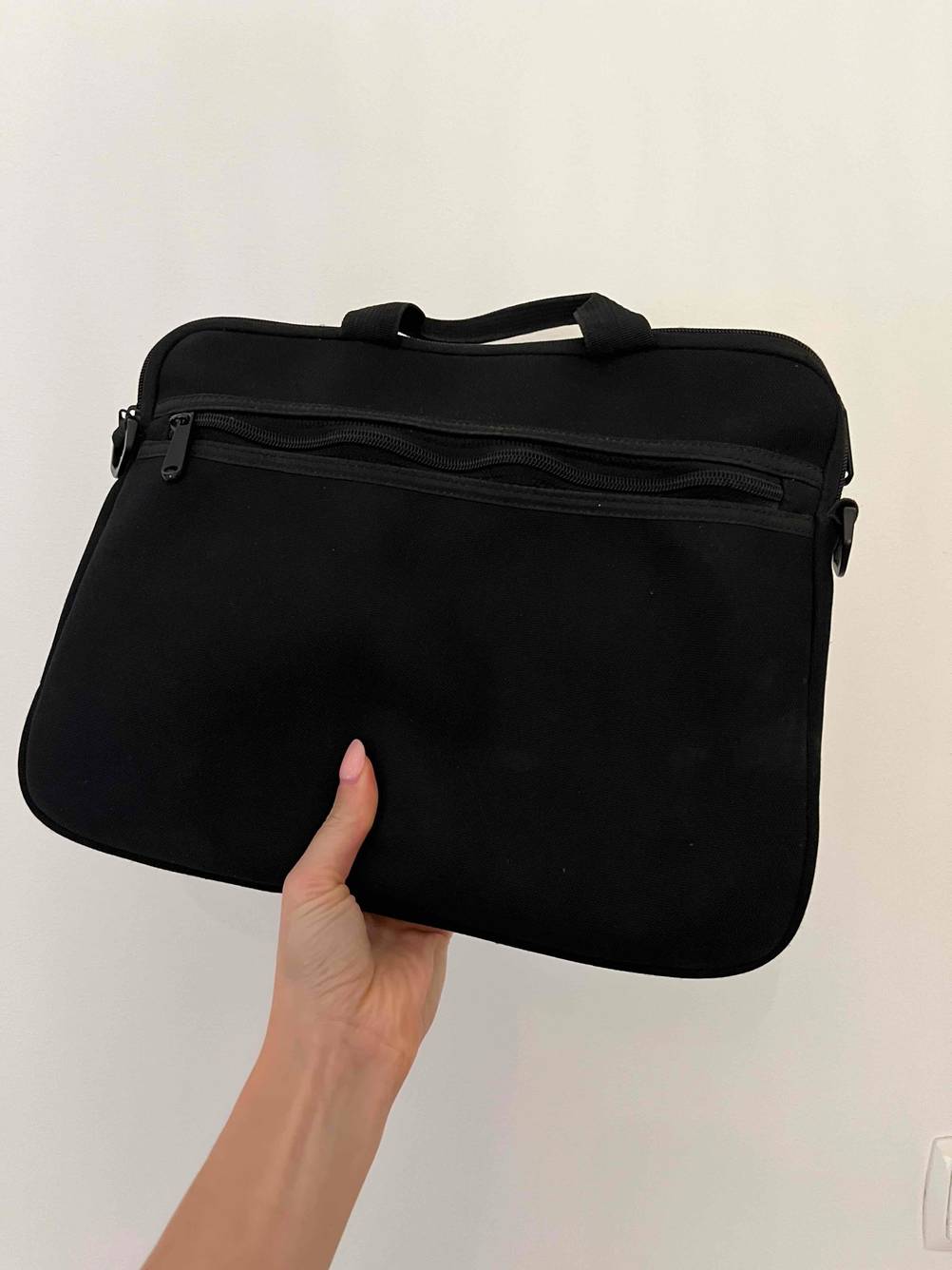 Hand hält eine getestete Tablet-Tasche in der Farbe Schwarz. 