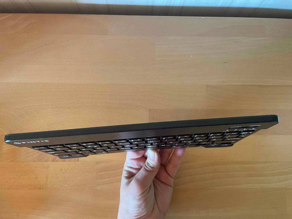 Eine Hand hält eine getestete Tablet-Tastatur so, daß die Dicke erkennbar ist.