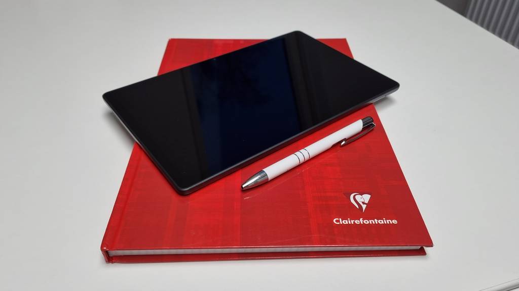 Ein Tablet im Test liegt auf einem roten Buch.