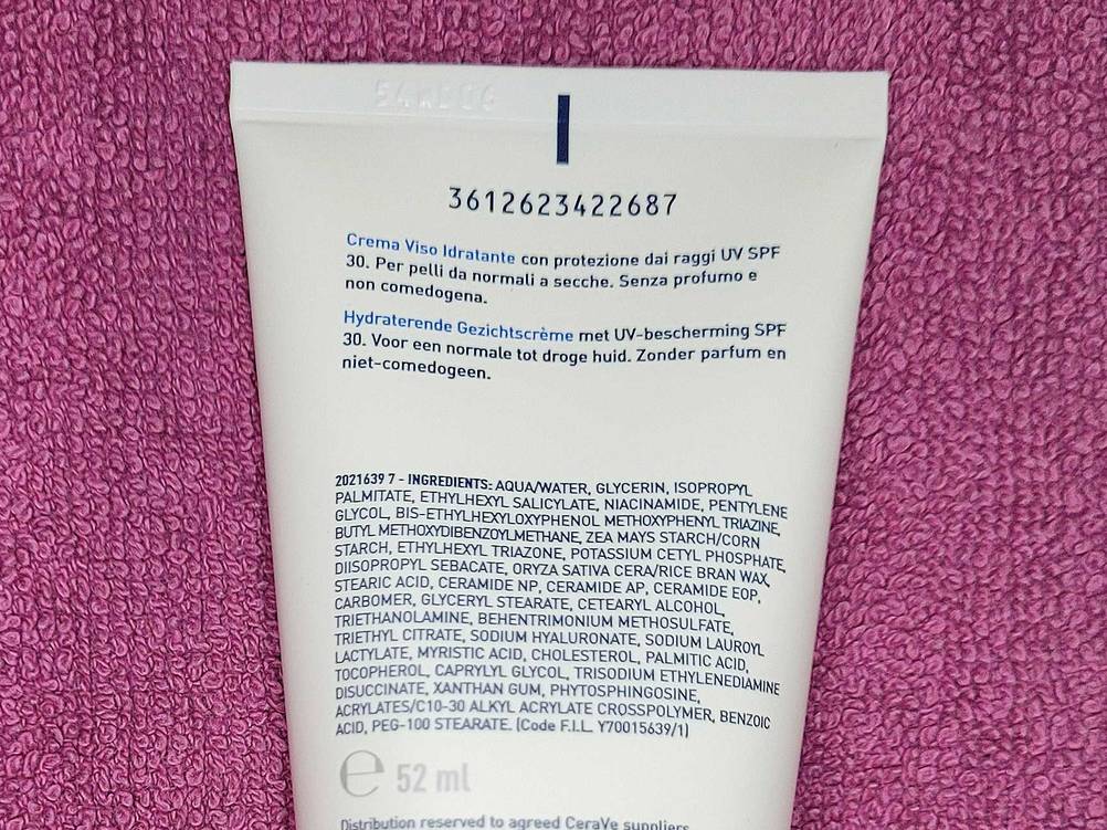 Nahaufnahme der Inhaltsstoffe auf der Rückseite der Tube der getesteten Tagescreme mit LSF auf rosa Handtuch.