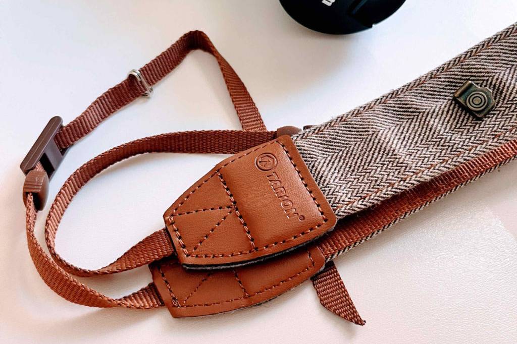 Im Test: Tairon Kamergurt liegt vor einer Canon-Kamera auf einem weißen Untergrund.