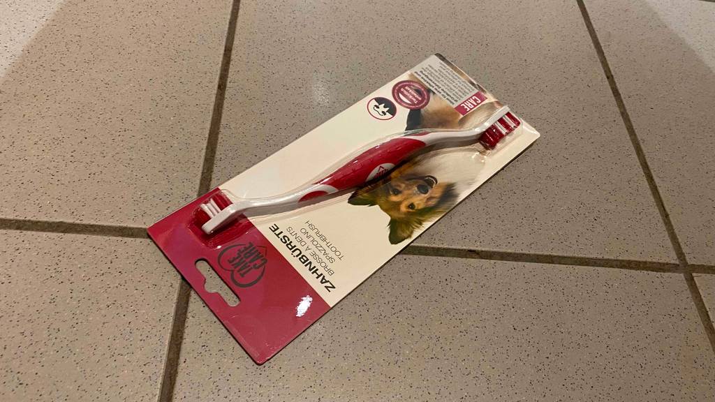 Hundezahnbürste im Test: Hundezahnbürste in der Verpackung liegt auf Fliesenboden.