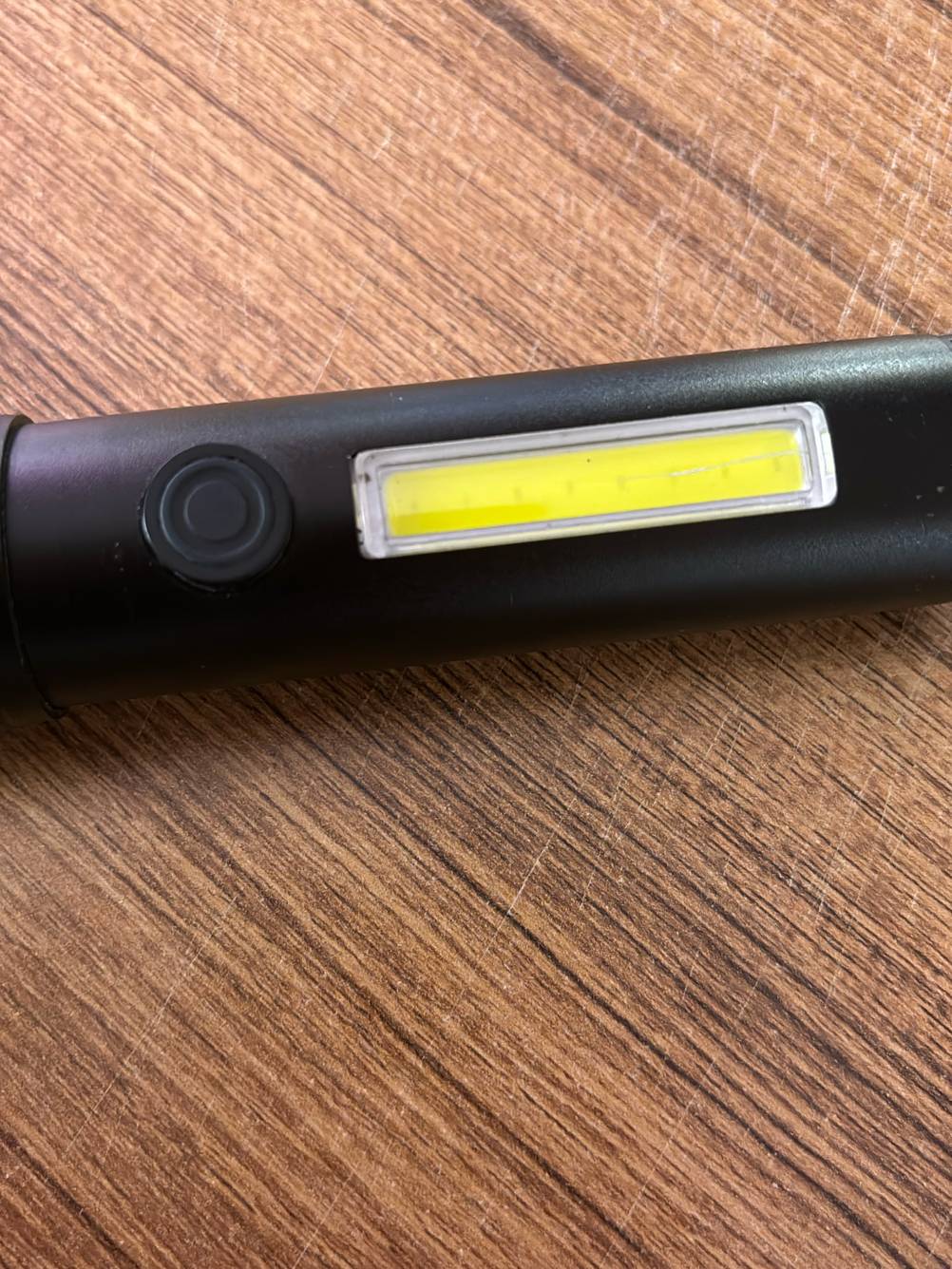 Detailansicht der Powertaste und Seitenlampe einer taktischen Taschenlampe im Test.