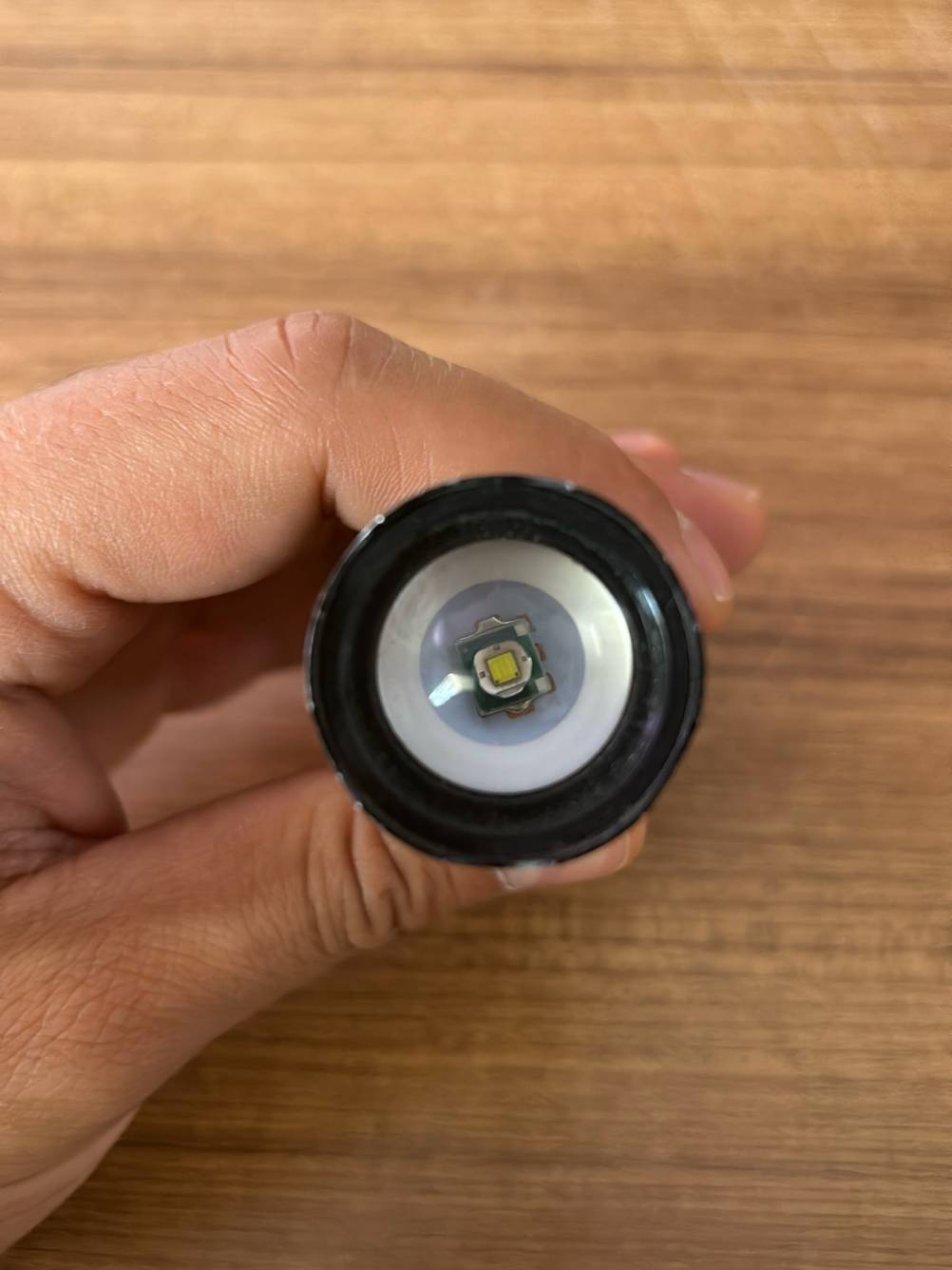 Blick von oben auf die Leuchteinheit einer getesteten taktischen Taschenlampe, die von einer Hand gehalten wird.