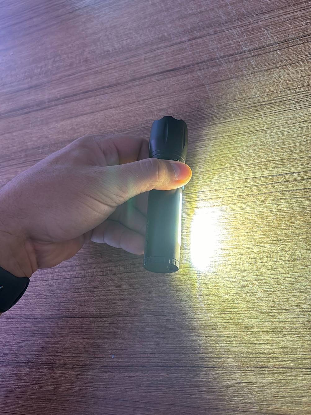 Im Test: Eine Hand hält eine taktische Taschenlampe, die mit der Seitenlampe auf den Boden leuchtet.
