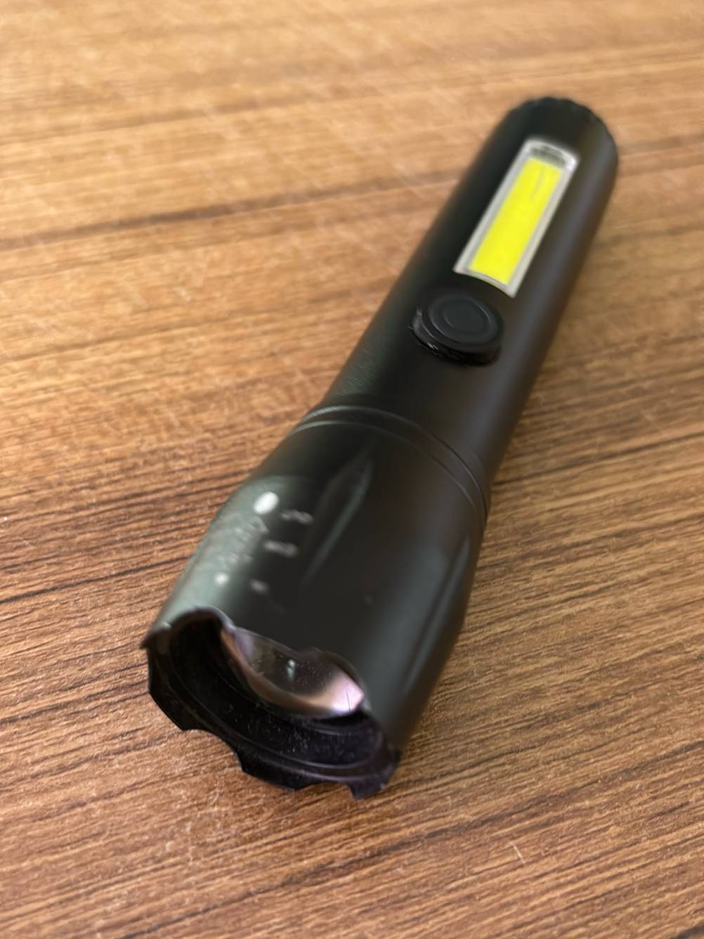 Eine taktische Taschenlampe liegt zum testen auf einem Holztisch.
