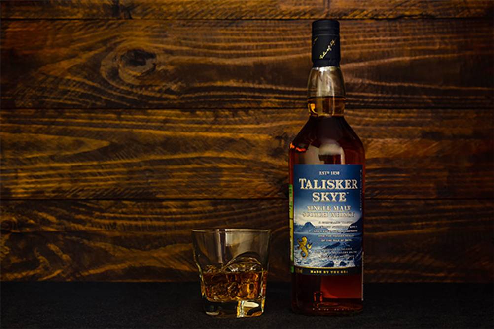 Talisker im Test: Hier der Talisker Skye vor einem hölzernen Hintergrund mit einem Glas.