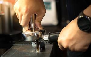Barista arbeitet mit getestetem Tamper. 
