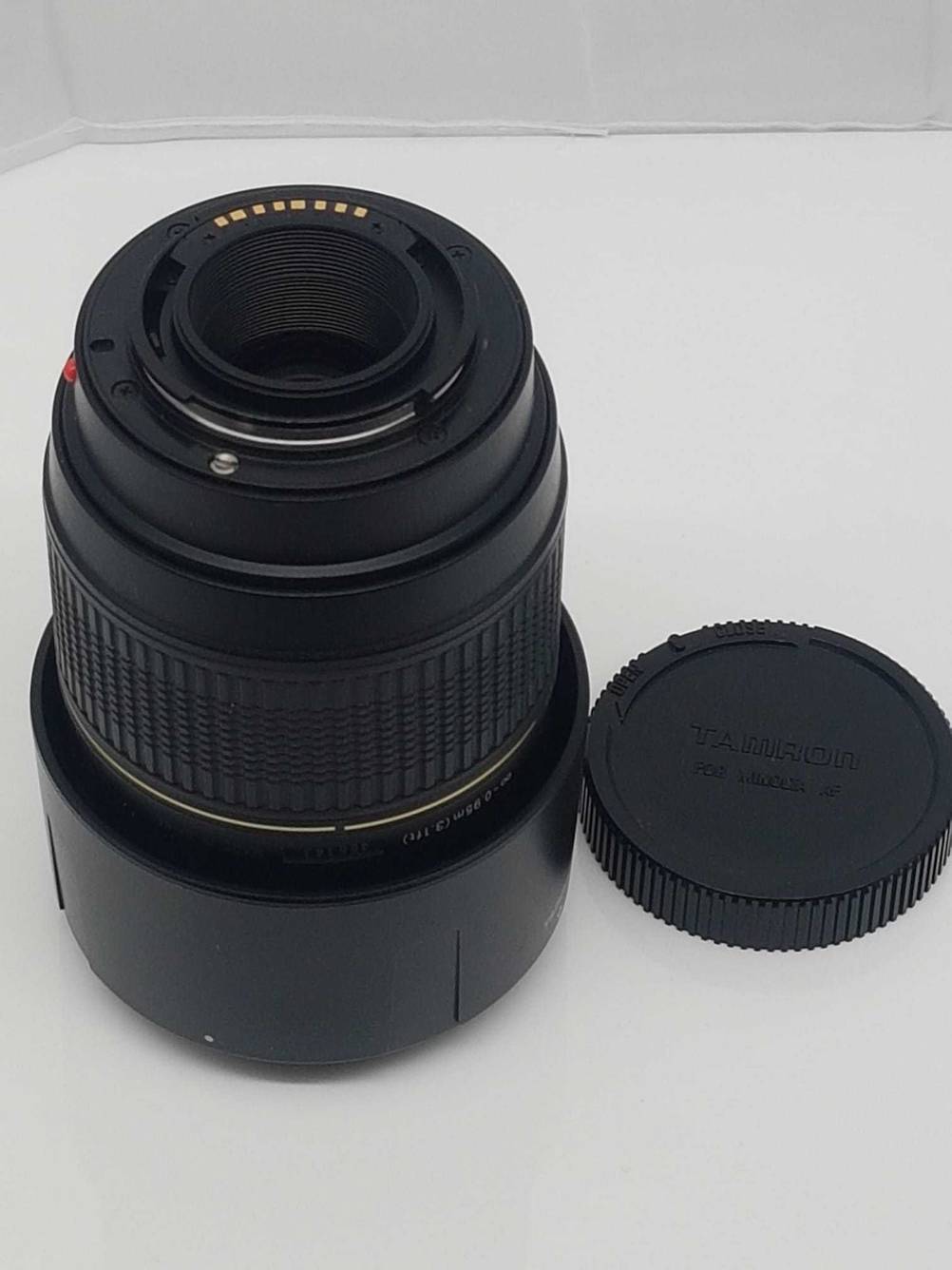 Im Test: Ein Tamron-Objektiv steht auf einer hellen Fläche mit dem Objektivanschluss nach oben, daneben liegt der Objektivdeckel.