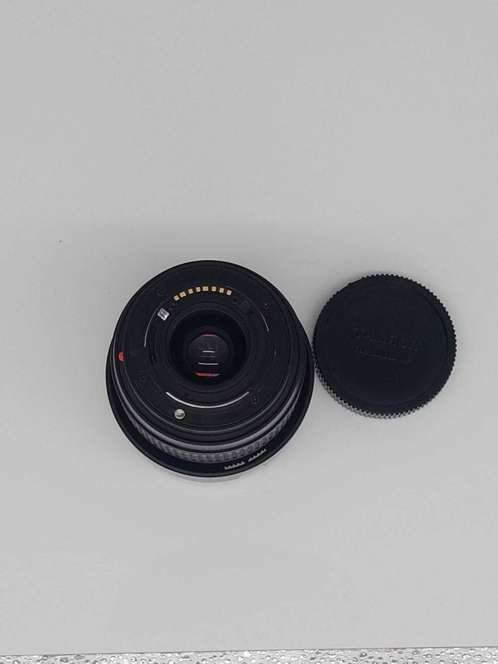 Ein Tamron-Objektiv im Test steht mit der Frontlinse nach unten auf einem Tisch, die Objektivkappe liegt daneben.