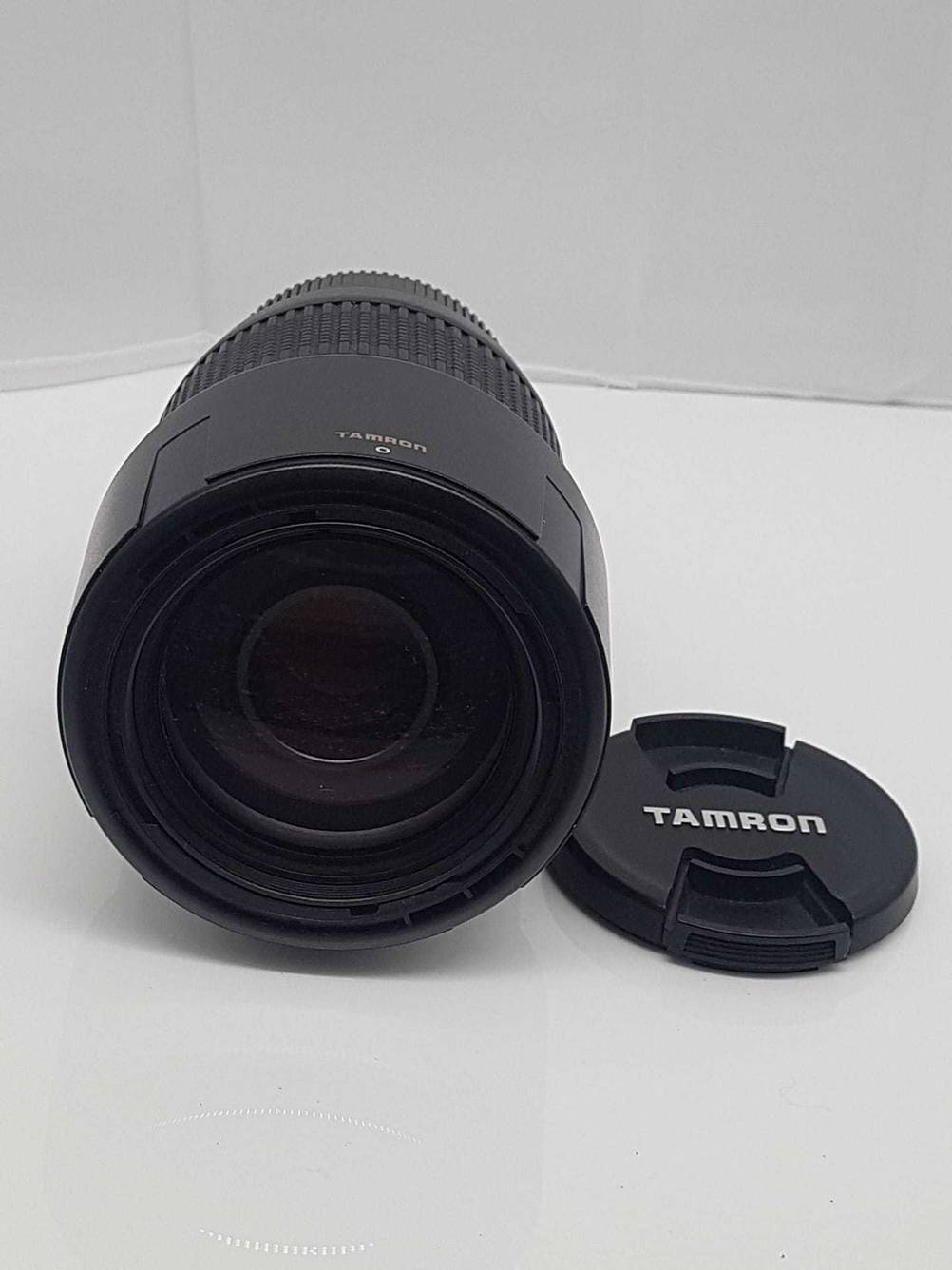Tamron-Objektiv-Test: Nahaufnahme auf die Frontlinse eines Objektives auf einer hellen Fläche daneben liegt der Objektivdeckel.