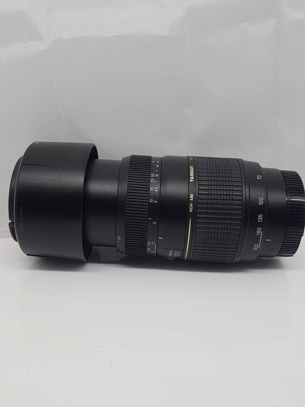 Tamron-Objektiv getestet: Ein ausgefahrenes Objektiv mit Gegenlichtblende und Objektivdeckel auf einer hellen Fläche liegend.