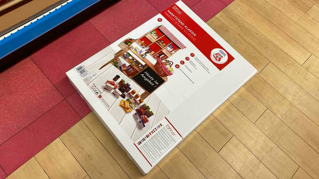 Kaufladen im Test: ein Marktstand des Typs Klassik von Tanner liegt in seiner Verpackung auf einem Holzboden.