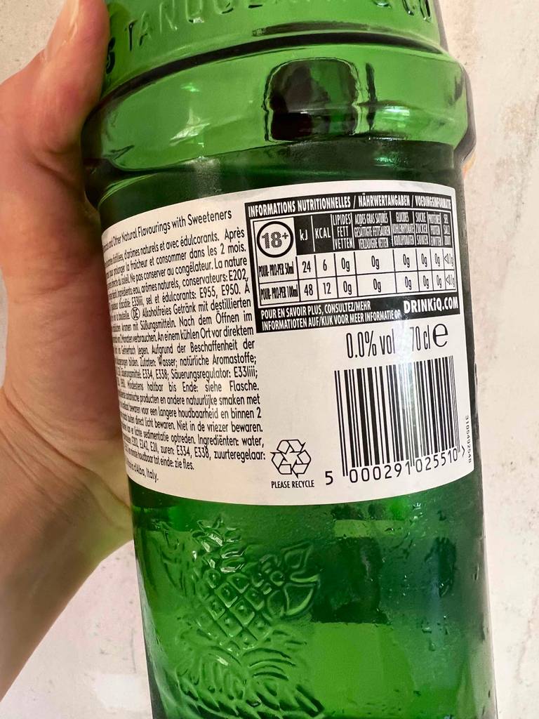 Eine Hand hält die Rückseite einer Flasche getesteten alkoholfreieren Gins nach oben.