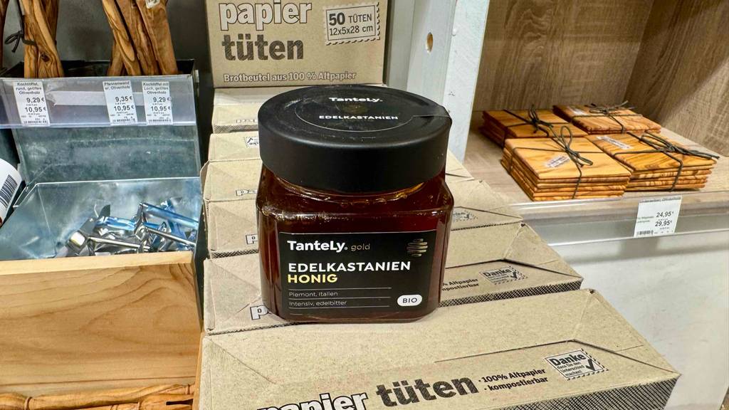 Kastanienhonig-Test: Ein Glas mit braunem Bio-Honig steht auf Lebensmittelkartons im Geschäft.