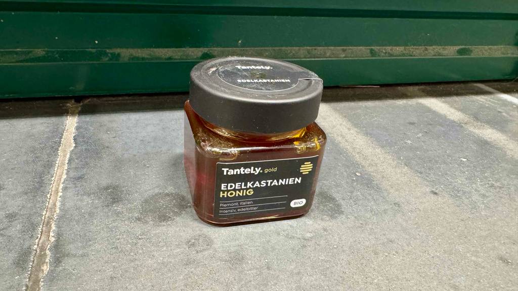 Im Test: Kastanienhonig im Glas mit braunem Inhalt steht auf dem Boden.